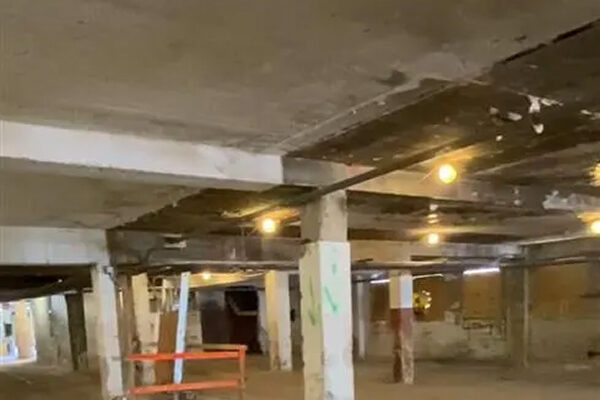 Empty concrete basement with dim light and a red barrier.