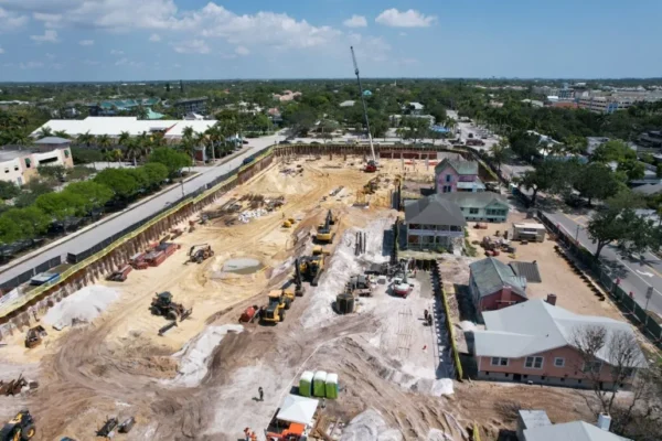 Aerial view of construction site with machinery and nearby homes.