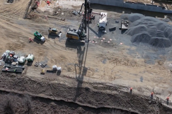Aerial view of construction site with machines and gravel piles.