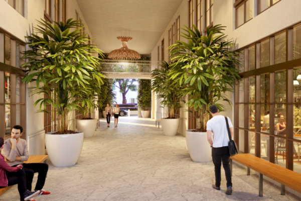 Corridor with benches, glass windows, plants, people, and sunlight.