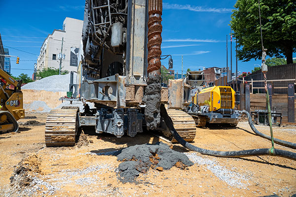 Drilling machine pours concrete at construction site foundation.