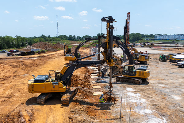 Excavators and drills work on earthmoving at a construction site.