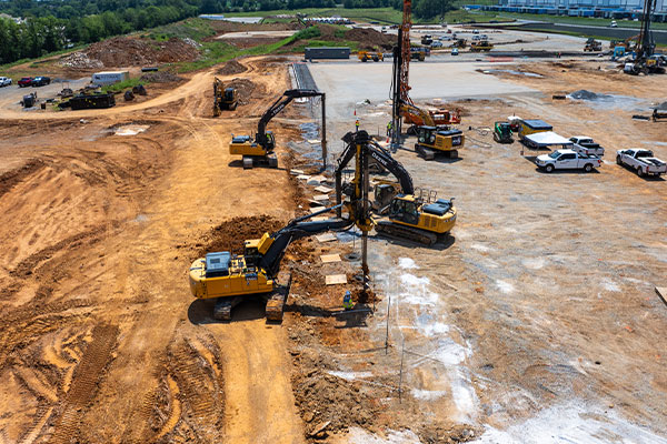 Aerial view of excavators and vehicles on reddish-brown construction site.