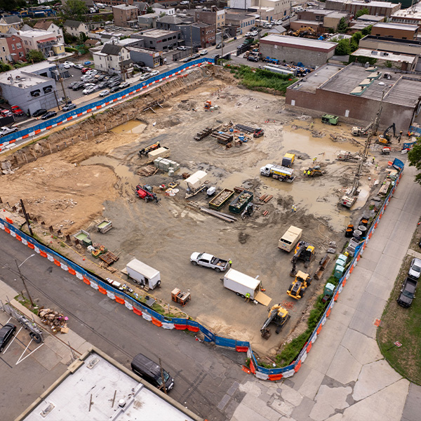 Aerial view of construction site with vehicles, equipment, orange-blue barrier.