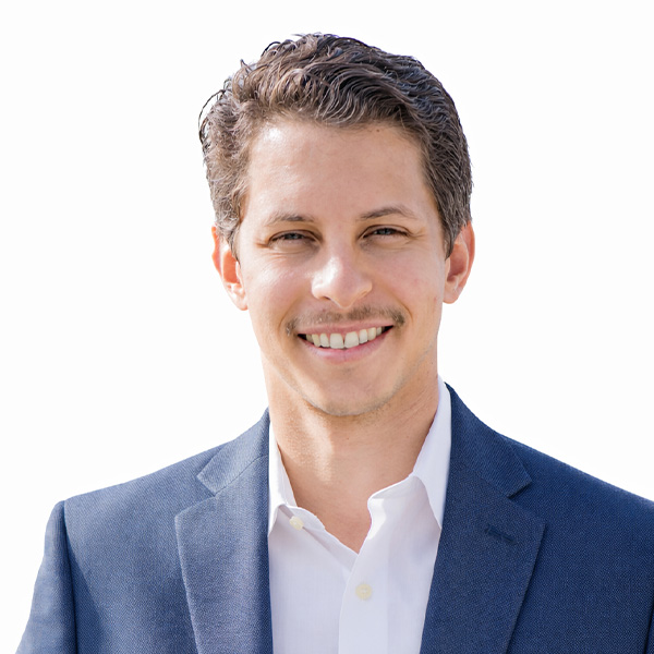 Smiling man in navy blazer and white shirt, white background.