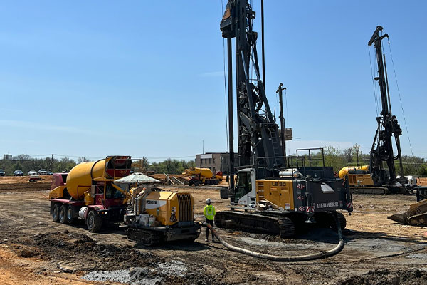 Construction site with drilling rigs, cement truck, and workers.