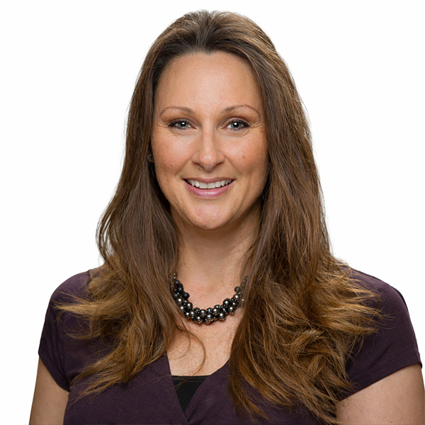Smiling woman in purple top with long brown hair.