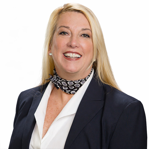 Smiling blonde woman in blazer and scarf on white background.